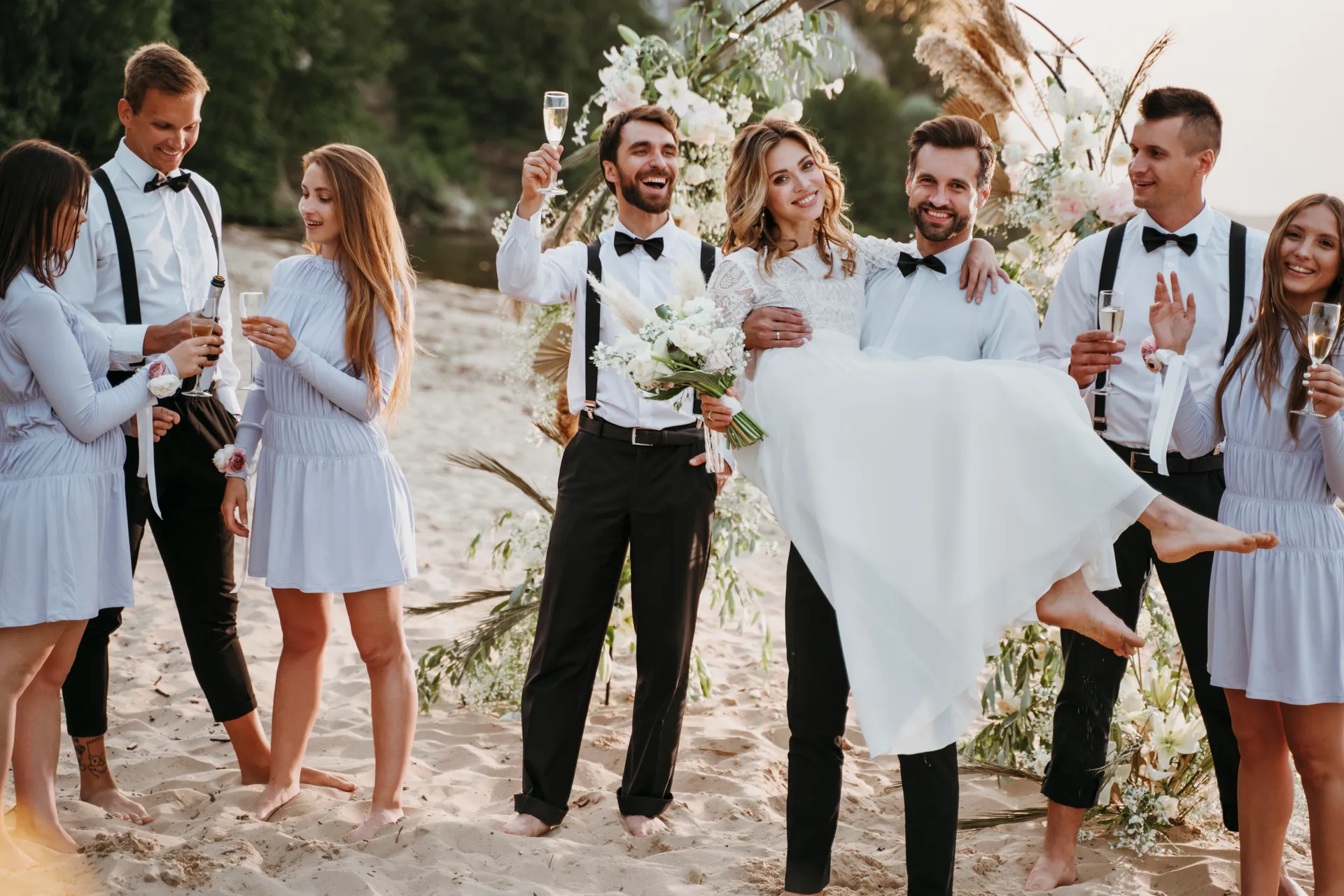 Bride and groom celebrating on the beach with their wedding guests