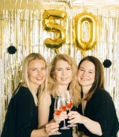 Three friends toasting with champagne at a 50th birthday party