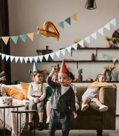 Children in party hats playing at a birthday party with bunting and balloons